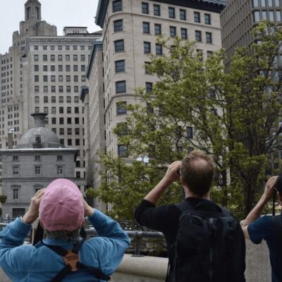 A group of people taking pictures of a city with tall buildings.