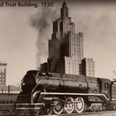 An old black and white photo of a train in front of a building.