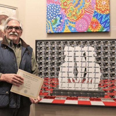 A man holding a certificate in front of a painting.