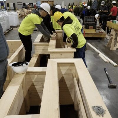 A group of people working on a wooden bench during Career and Technical Education Month at Mt. Hope High School.