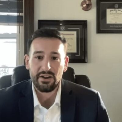 A man in a suit sitting in front of a desk.