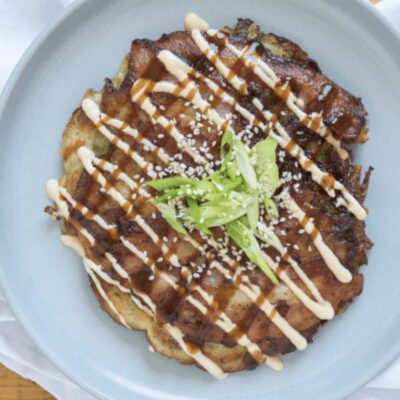 A recipe for a plate topped with a pancake with sauce and sesame seeds.