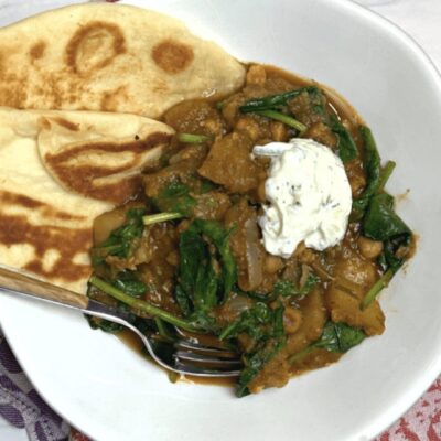 Recipe: A flavorful bowl of spinach curry topped with pita bread and a dollop of sour cream.