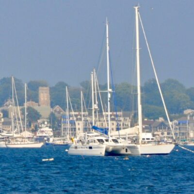 A group of sailboats with women in business on board sailing in the water.
