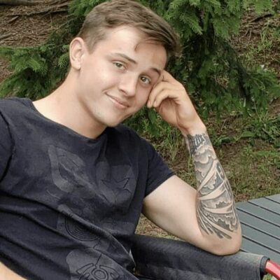 A young man sitting on a lawn chair with AEW tattoos.