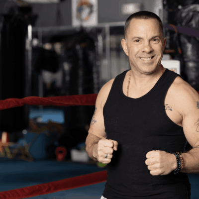 A man in a tank top standing in front of a boxing ring.
