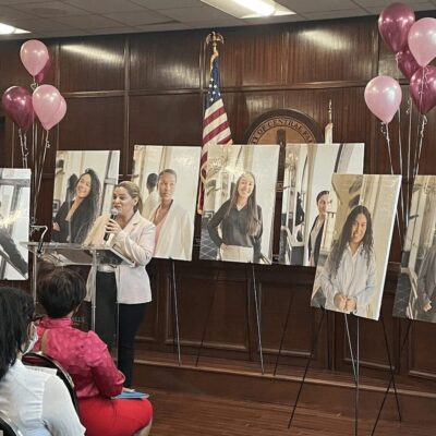 A group of women from Central Falls standing in front of a podium with balloons.