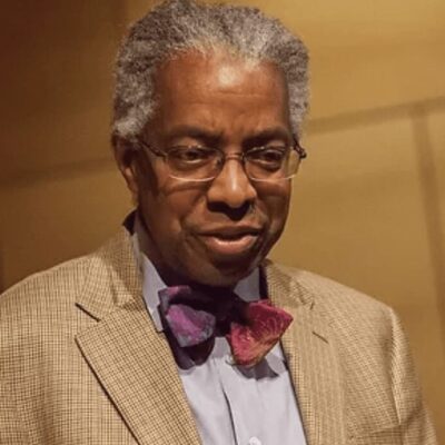 A man of race wearing glasses and a bow tie.