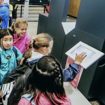 A group of children standing in line at an Ocean Race Newport airport.
