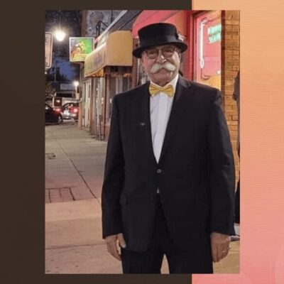 A man in a tuxedo standing on a sidewalk outside the DaVinci Center.