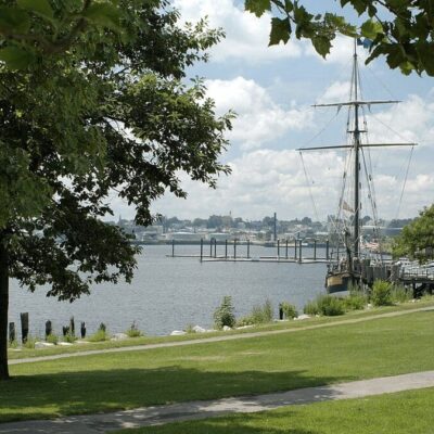A boat is docked in a park near a body of water.