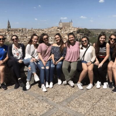 A group of girls posing for a photo in front of a city.