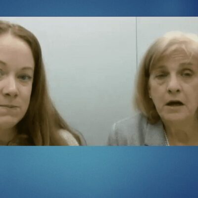 Two women are talking in front of a blue background at a day care in Rhode Island.