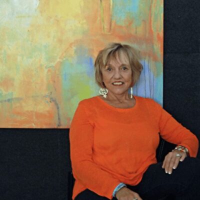 A woman sitting on a chair in front of a painting.