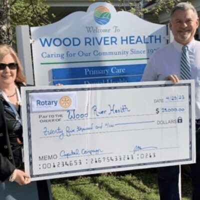 A man and woman holding a check for wood river health.