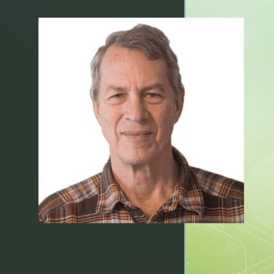 A man in a plaid shirt with a green background.