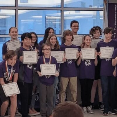 A group of people holding certificates in front of a group of people.