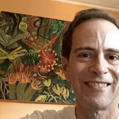 A man smiling in front of a painting.