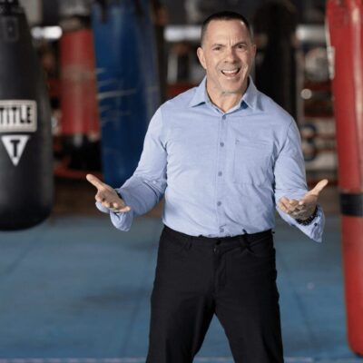 A man standing in front of a boxing ring, demonstrating fitness and exercise techniques in Rhode Island for Burn with Kearns.