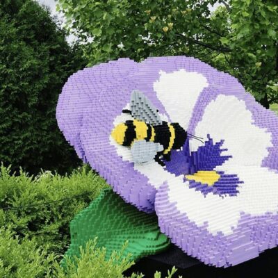 A Lego pansy adorned with a tiny bee.