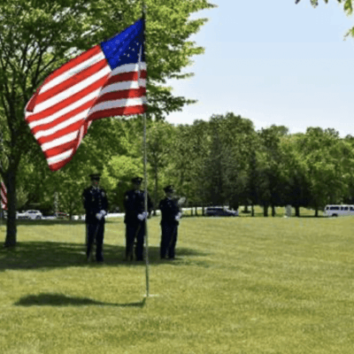 A group of veterans standing on a grassy field with an American flag.