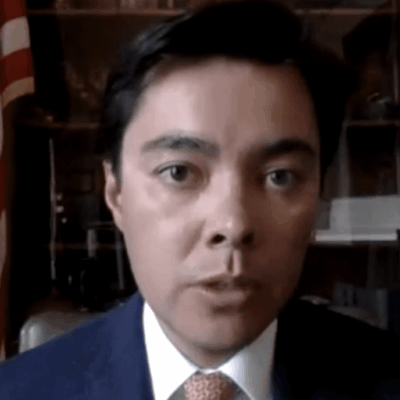 A man in a suit and tie in front of an american flag.