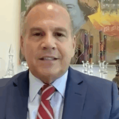 A man in a suit and tie is sitting in front of a desk.