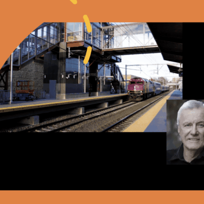 An image of a man standing next to a train station, with a train in the background.