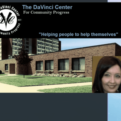 A woman is standing in front of a building with the words the DaVinci Center helping people to help themselves.