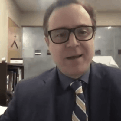A man in a suit and tie is sitting in front of a desk.