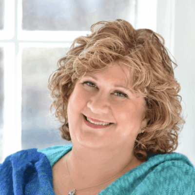 A woman smiling in front of a window.
