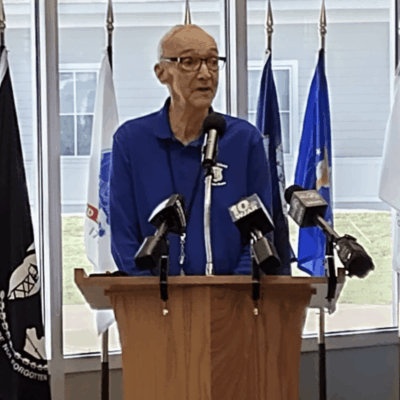 A man standing at a podium addressing veterans.