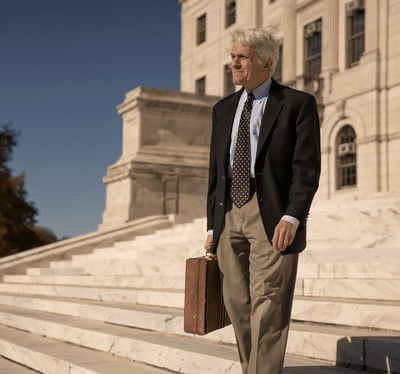 A man from GrowSmartRI with a briefcase walking down a set of steps.