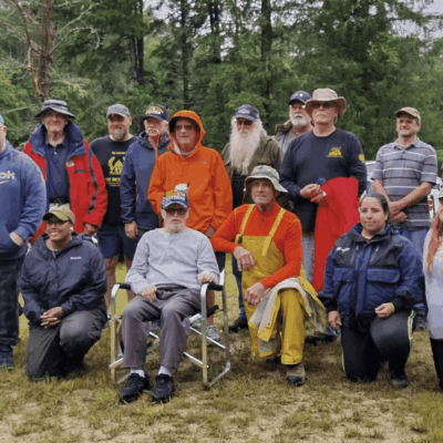 A group of veterans posing for a photo while fly fishing.