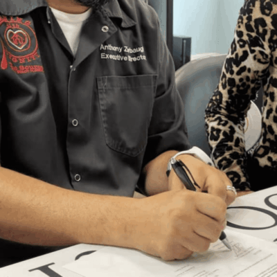 A man and woman signing a document at a table.