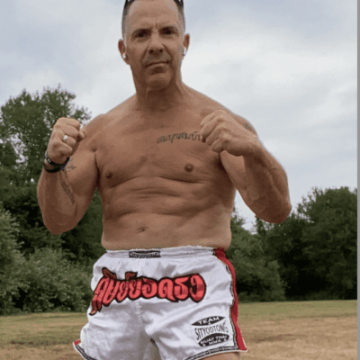 A man in boxing shorts posing in a field.