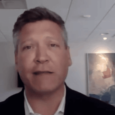 Christopher Marsella, a man in a suit, standing in front of a wall.