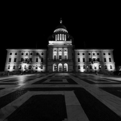 A black and white photo of a building at night, portraying an urban atmosphere.
