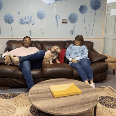 A man and woman sitting on a couch with a dog.