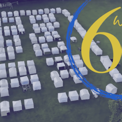 An art festival showcasing a group of tents arranged in a field with the words we're 60.