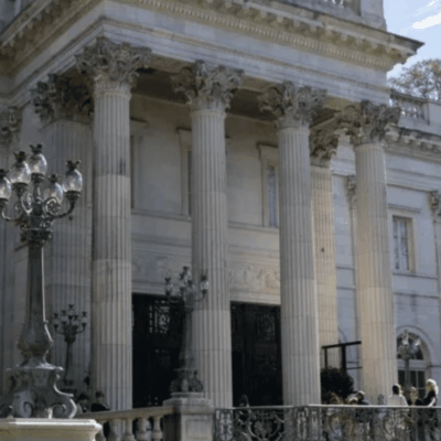 One of the majestic Newport mansions, a large white building with striking columns and elegant pillars, stands magnificently.