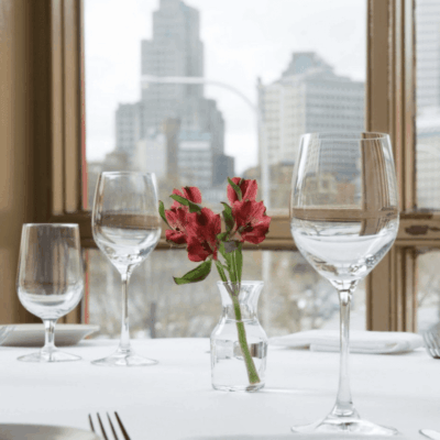 A table set with wine glasses and a vase of flowers in a restaurant.