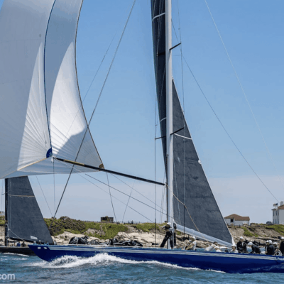 Two sailboats are racing in the water near a lighthouse in Newport, RI.