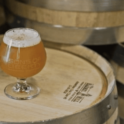 A glass of beer sitting on top of barrels.