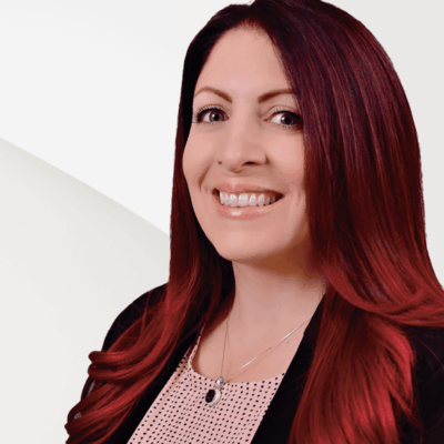 A woman with red hair smiling in front of a white background, representing Engel & Volkers real estate agency.