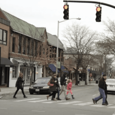 A group of people crossing a street with architectural background.