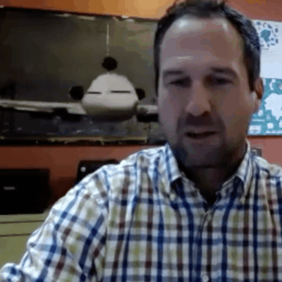 A man in a plaid shirt is sitting in front of a computer.
