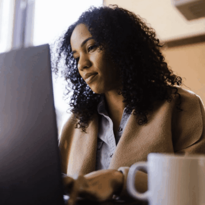 A woman working on a laptop in a coffee shop.