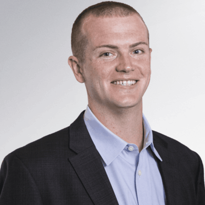 A man in a suit, possibly involved in Providence sports, is smiling.