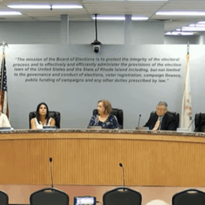 Sabina Matos and a group of people sitting at a table in a meeting room.